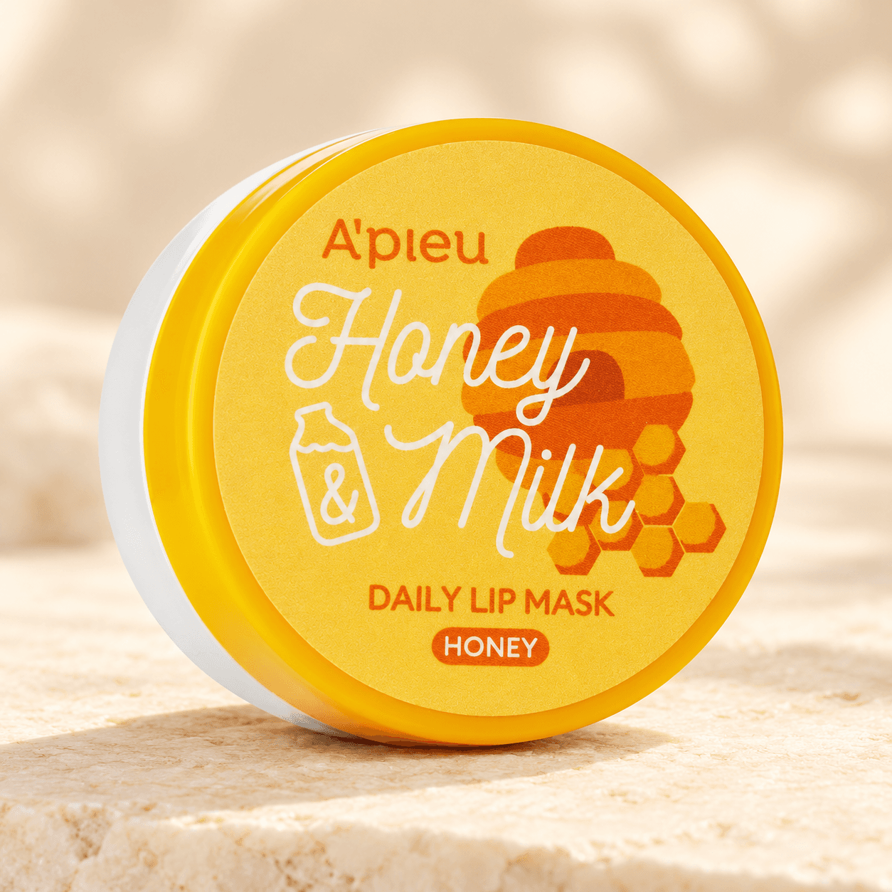A’pieu Honey & Milk Daily Lip Mask Honey 6 g — composição ilustrativa da embalagem num ambiente de cuidados labiais